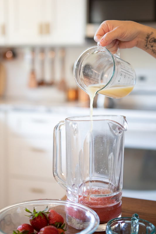pouring lemon juice into a pitcher