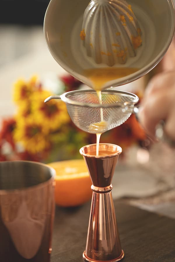 orange juice pouring into jigger