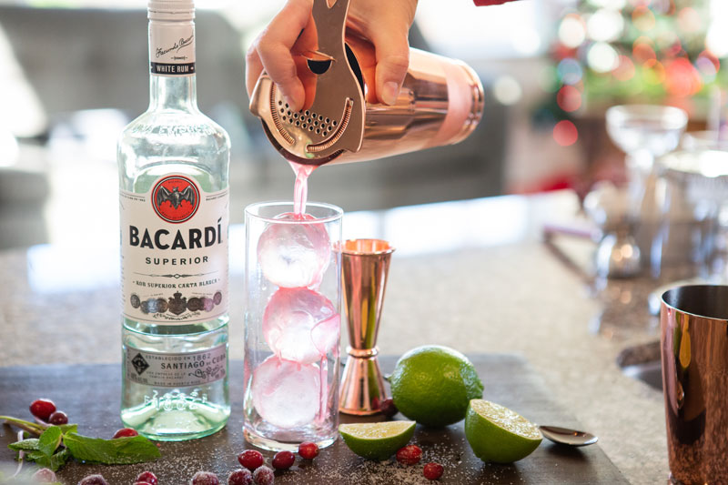 cocktail pouring into glass with ice cubes